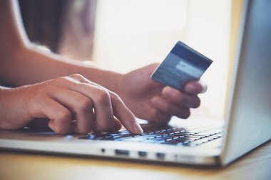 Person foran sin computer med kreditkort i hånden, som er klar til at handle på Black Friday